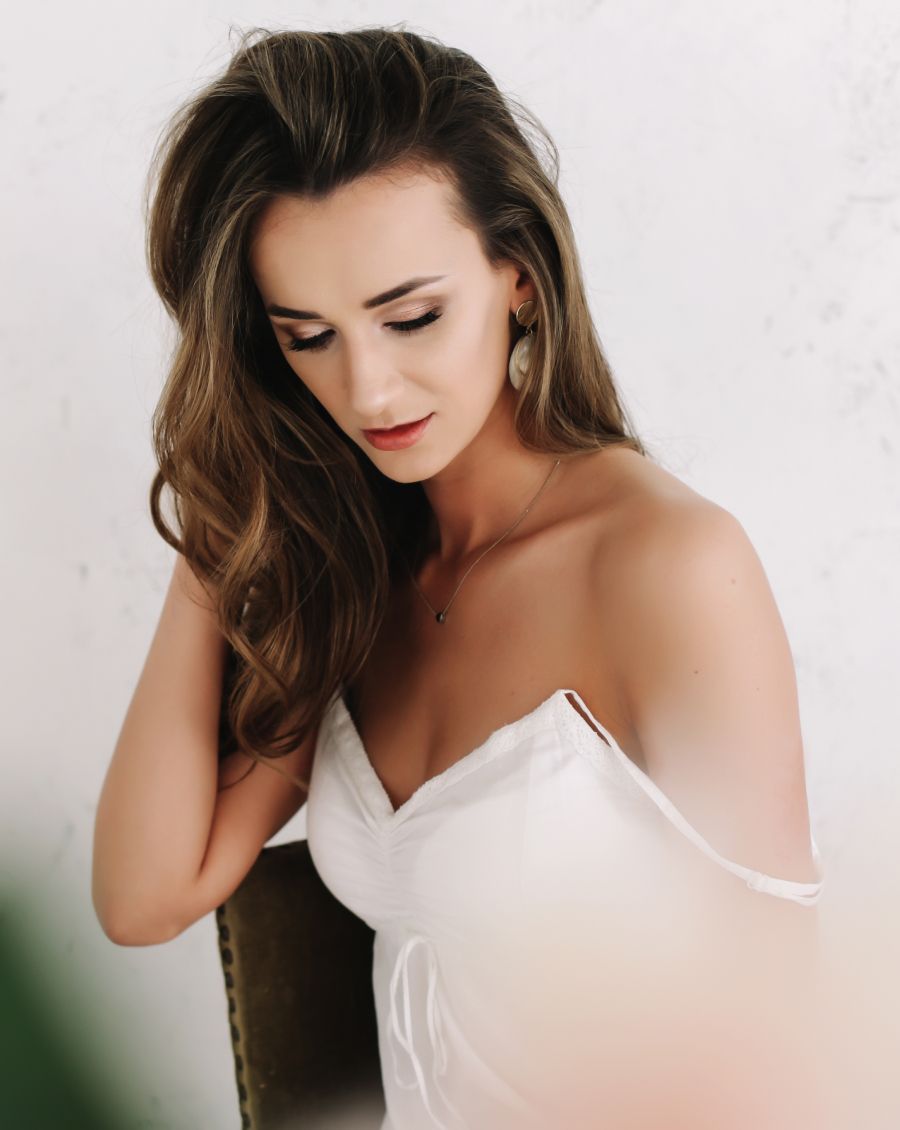 Phoenix plastic surgery model with long hair in white outfit, contemplative.